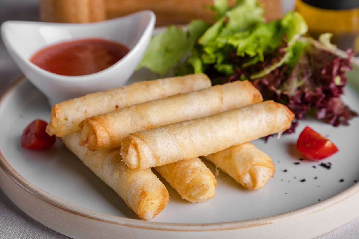 Chả giò chiên giòn bày trên đĩa ăn kèm rau sống và chanh