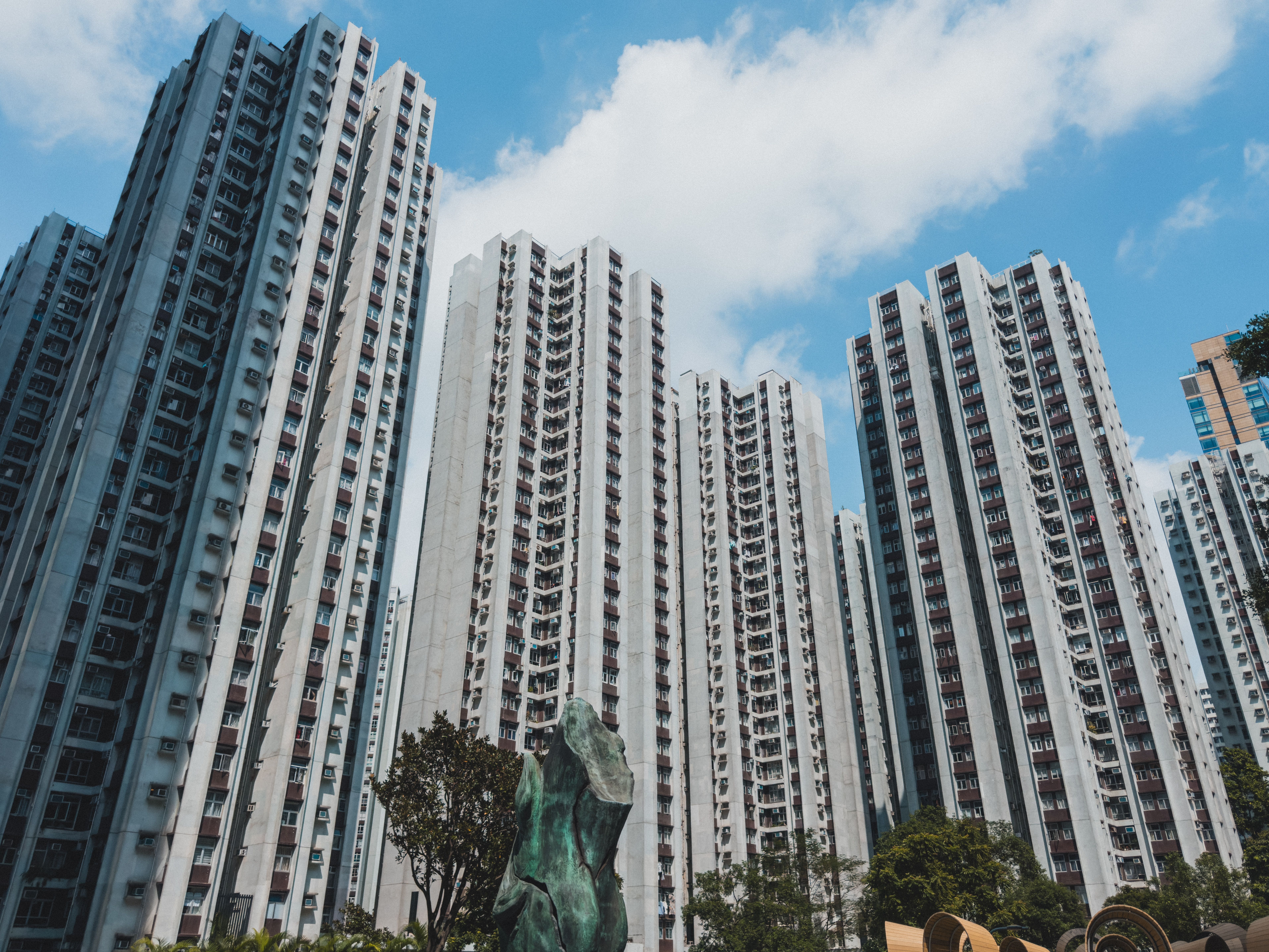 High-rise residential buildings against a blue sky in Hong Kong cityscape.