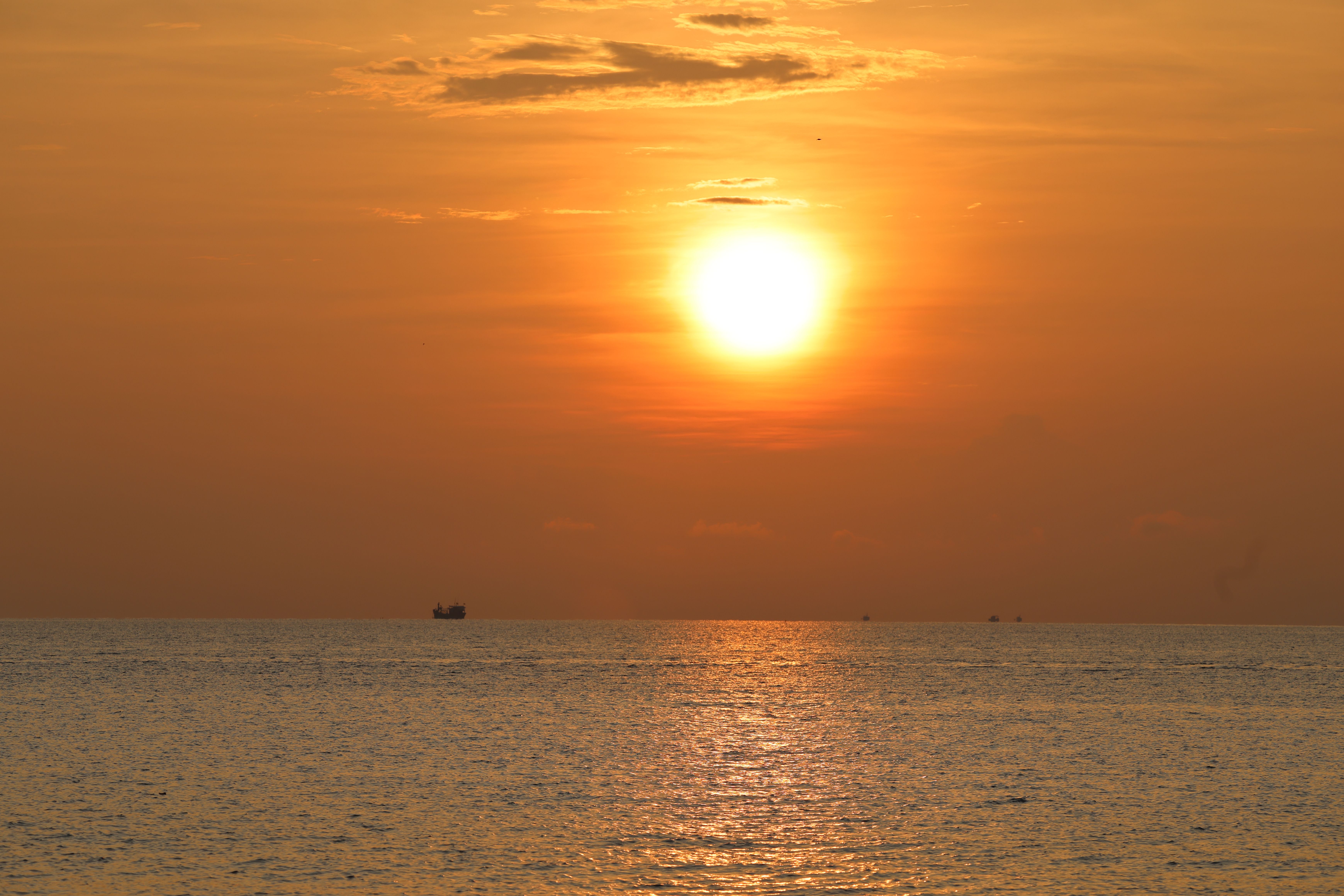 A vibrant sunset over the ocean in Vietnam, casting warm hues across the water.