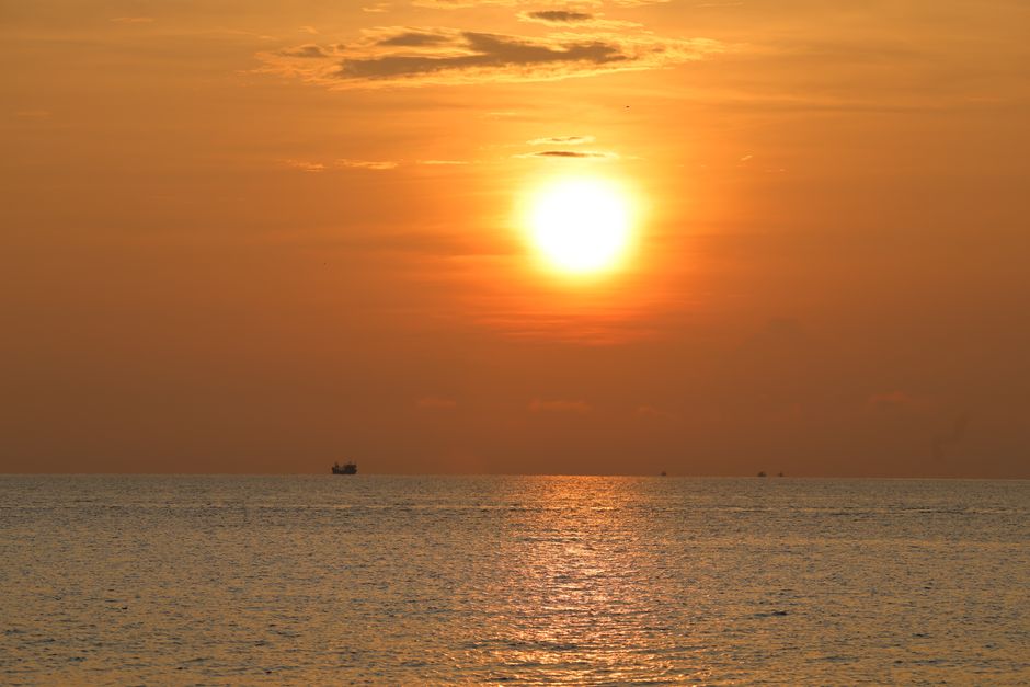 A vibrant sunset over the ocean in Vietnam, casting warm hues across the water.