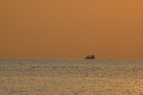 Free A solitary ship sails on the calm sea under a dramatic orange sunrise in Vietnam. Stock Photo