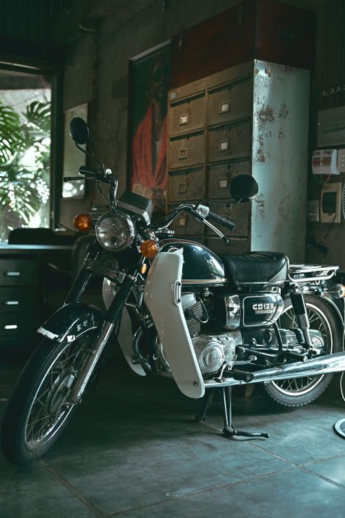 Free A classic vintage motorcycle parked indoors with a rustic ambiance and natural lighting. Stock Photo