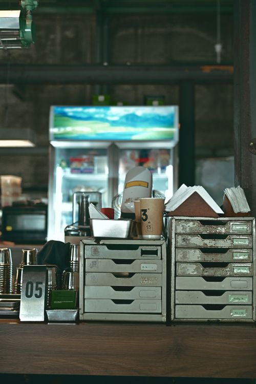 Free A rustic cafe setting with neatly arranged drawers, napkins, and a view of a fridge in the background. Stock Photo