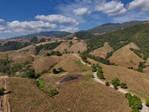 Free Stunning aerial view of rolling hills and mountain landscapes in Chiang Mai, Thailand under a bright blue sky. Stock Photo