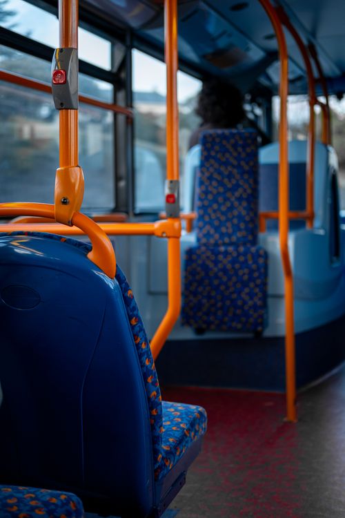 Free A quiet interior of a public bus with vibrant blue and orange seating, United Kingdom. Stock Photo