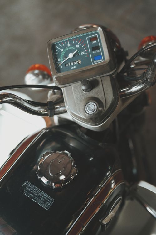Free Close-up of a vintage motorcycle dashboard with analog speedometer in an indoor garage setting. Stock Photo
