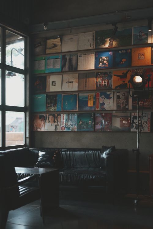 Free A cozy lounge featuring a wall of colorful vinyl records, leather sofas, and a vintage floor lamp. Stock Photo