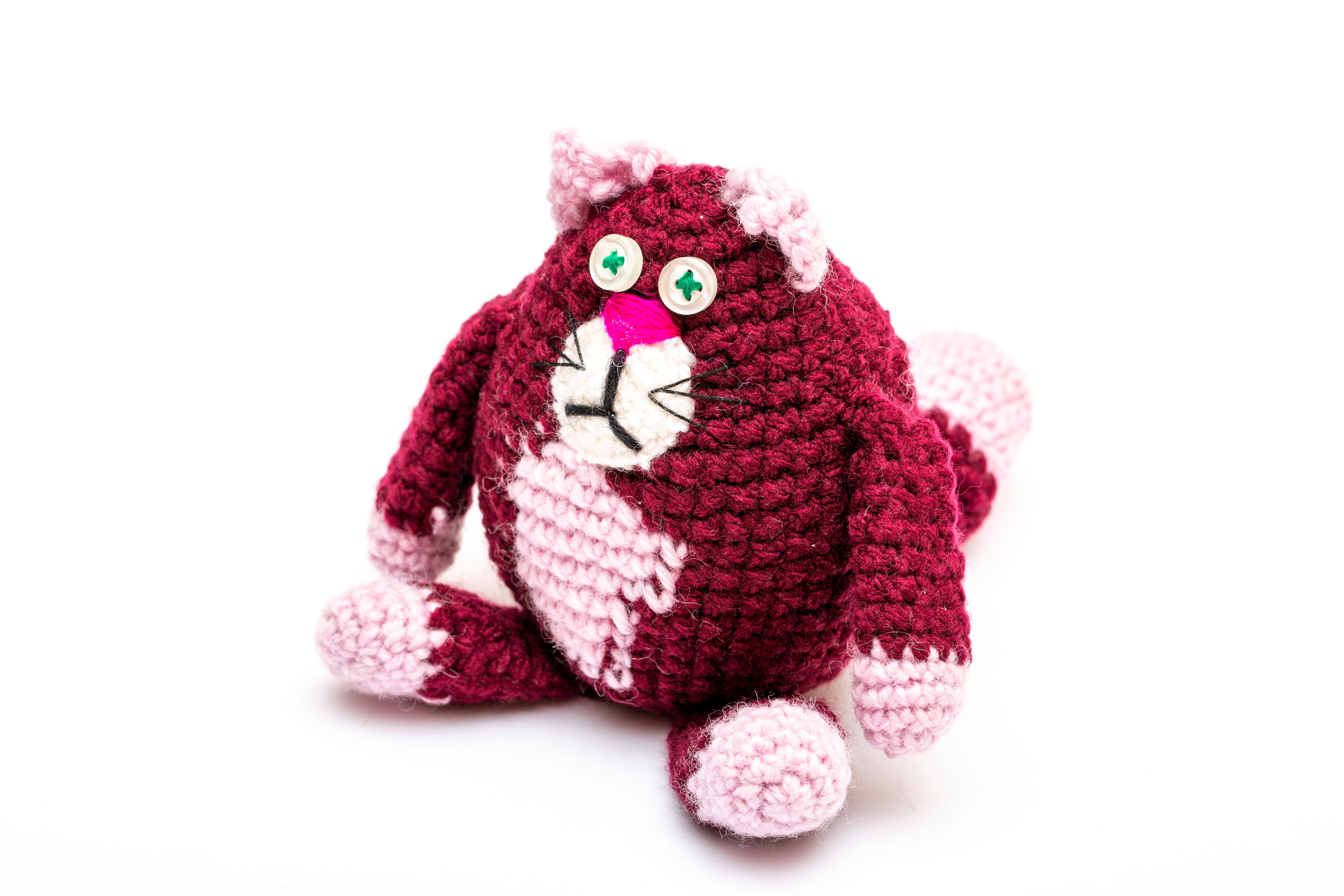 Adorable handmade crocheted cat toy in red and pink yarn, perfect for decoration or child's play.