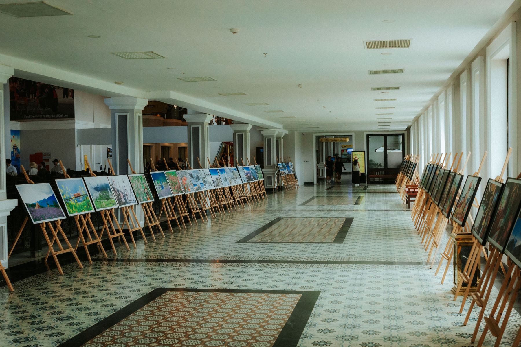 Gallery hallway with student artwork displayed on easels under exhibition lighting