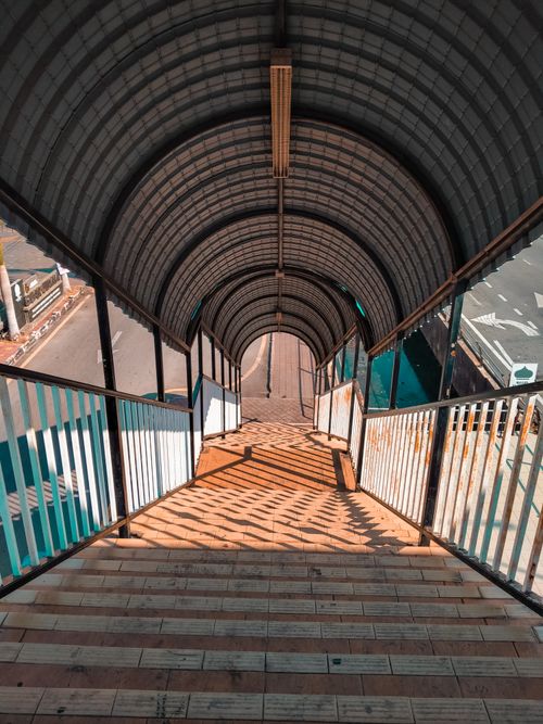 Free A covered footbridge with geometric shadow patterns and striped railings. Stock Photo