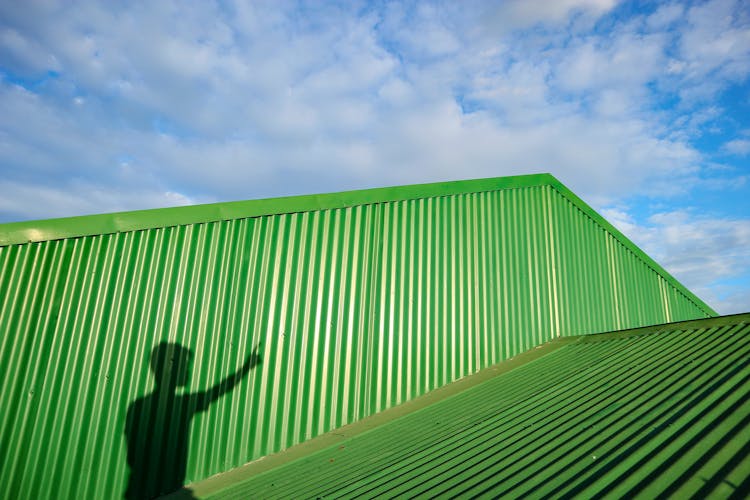 Shadow Of Anonymous Man On Green Metal Construction In Sunlight