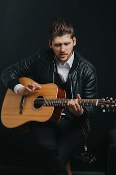 Portrait of a man passionately playing an acoustic guitar in a studio setting.