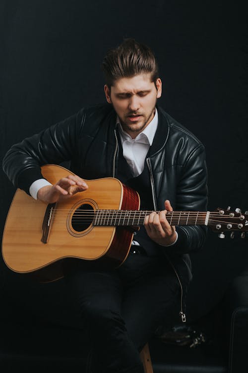 Man In Black Jacket Playing Brown Acoustic Guitar