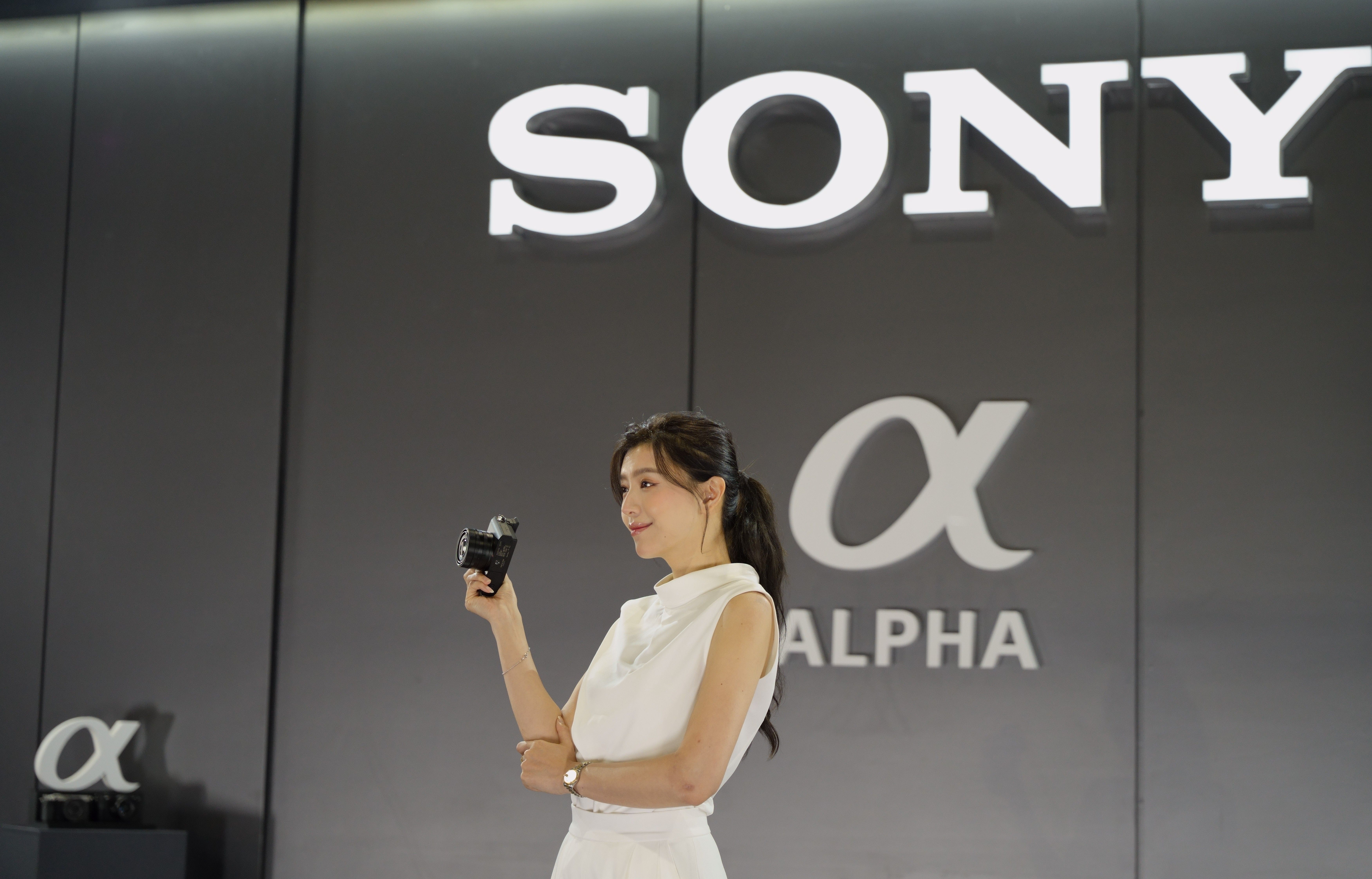 Woman in white posing with camera at Sony showcase in Taipei, Taiwan.
