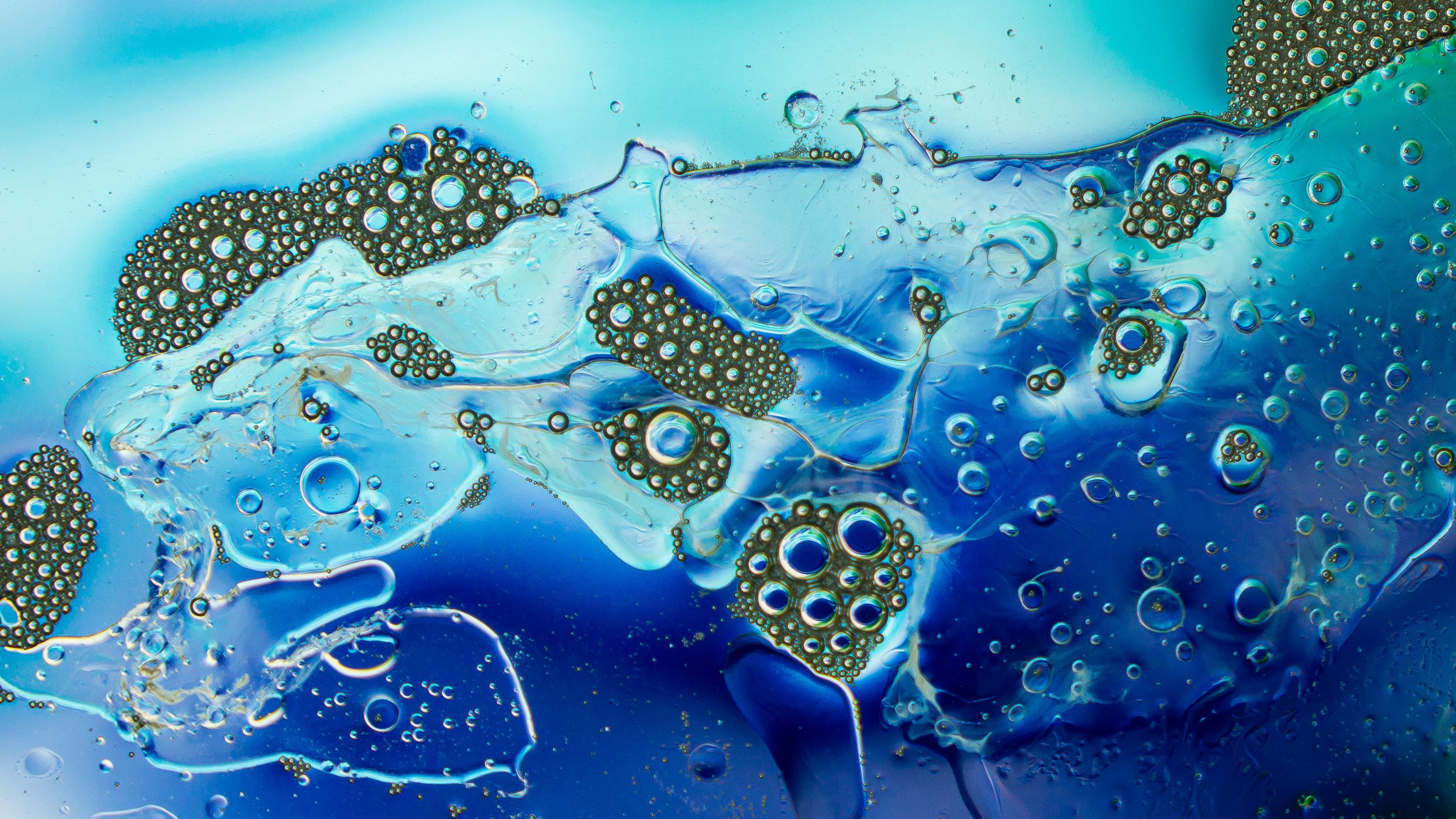 Close-up view of oil and water bubbles creating an abstract pattern with vibrant blue tones.