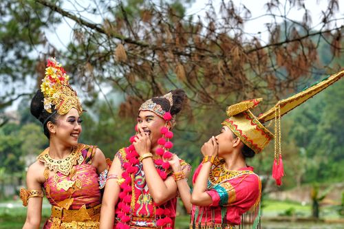 Free Three women in vibrant traditional Indonesian dance costumes, laughing in a lush outdoor setting, West Java. Stock Photo