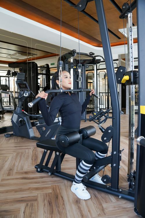 Free Woman working out using a lat pulldown machine in a modern gym setting. Stock Photo