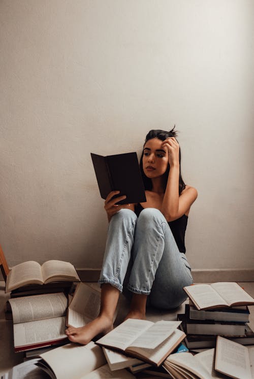 Woman In Black Tank Top And Denim Jeans Reading A Book