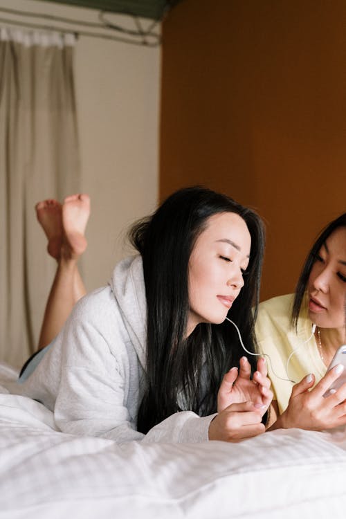 Free Woman in Gray Hoodie Sitting on Bed Stock Photo