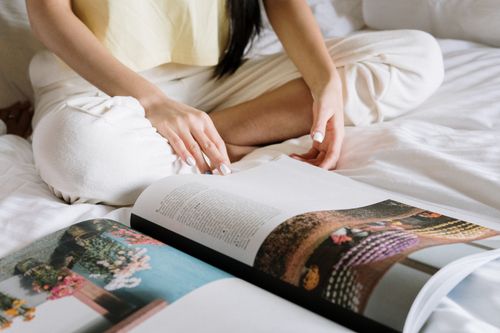 Free A person sits cross-legged on bed, reading a magazine, showcasing a cozy home environment. Stock Photo