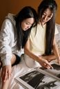 两名年轻女子在舒适的家庭环境中一同阅读，捕捉到了友谊与放松的时刻