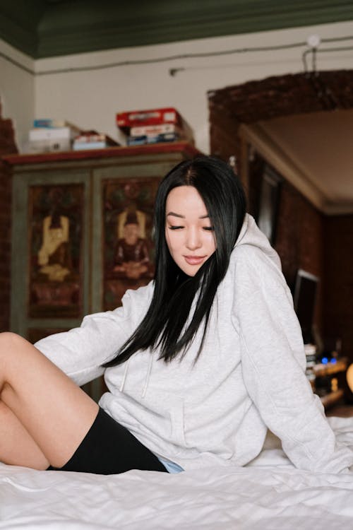 Free Woman in White Hoodie Sitting on Brown Wooden Chair Stock Photo