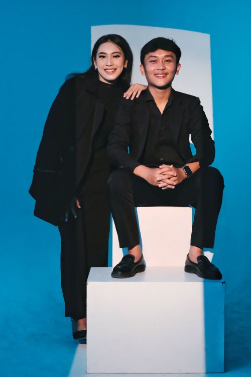 Free Stylish portrait of two adults posing confidently against a blue background in Garut, Indonesia. Stock Photo