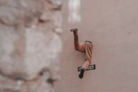 Half body of unrecognizable man escaping through hole in wall