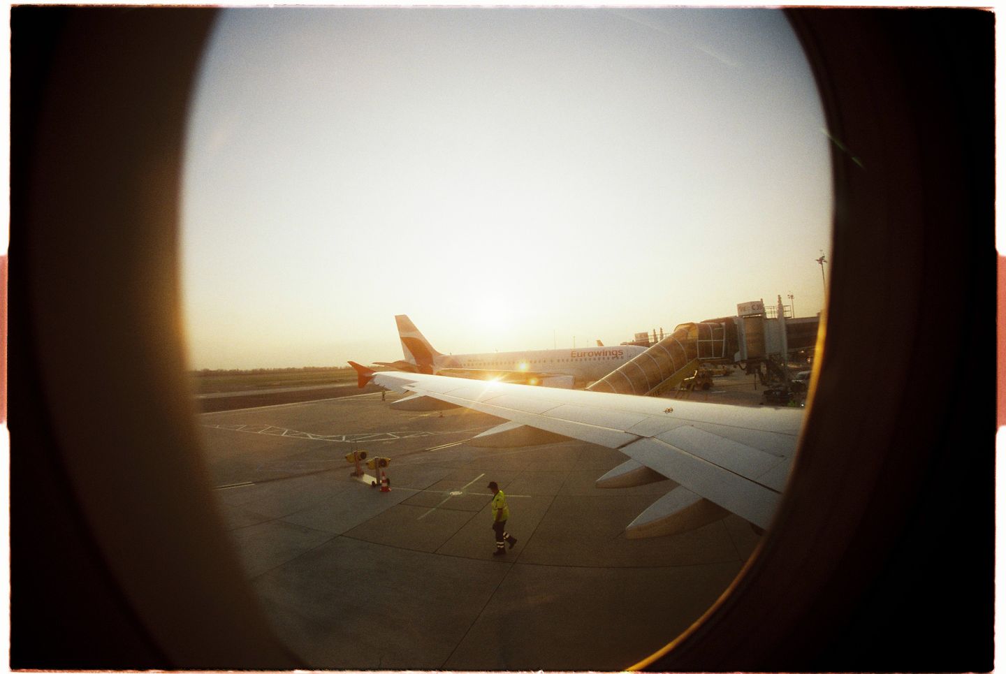 해 뜰 무렵 비행기 창밖으로 보이는 공항 터미널과 날개