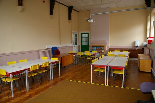 Free Spacious classroom with yellow chairs, desks, projector, and wooden floor, ideal for learning environments. Stock Photo