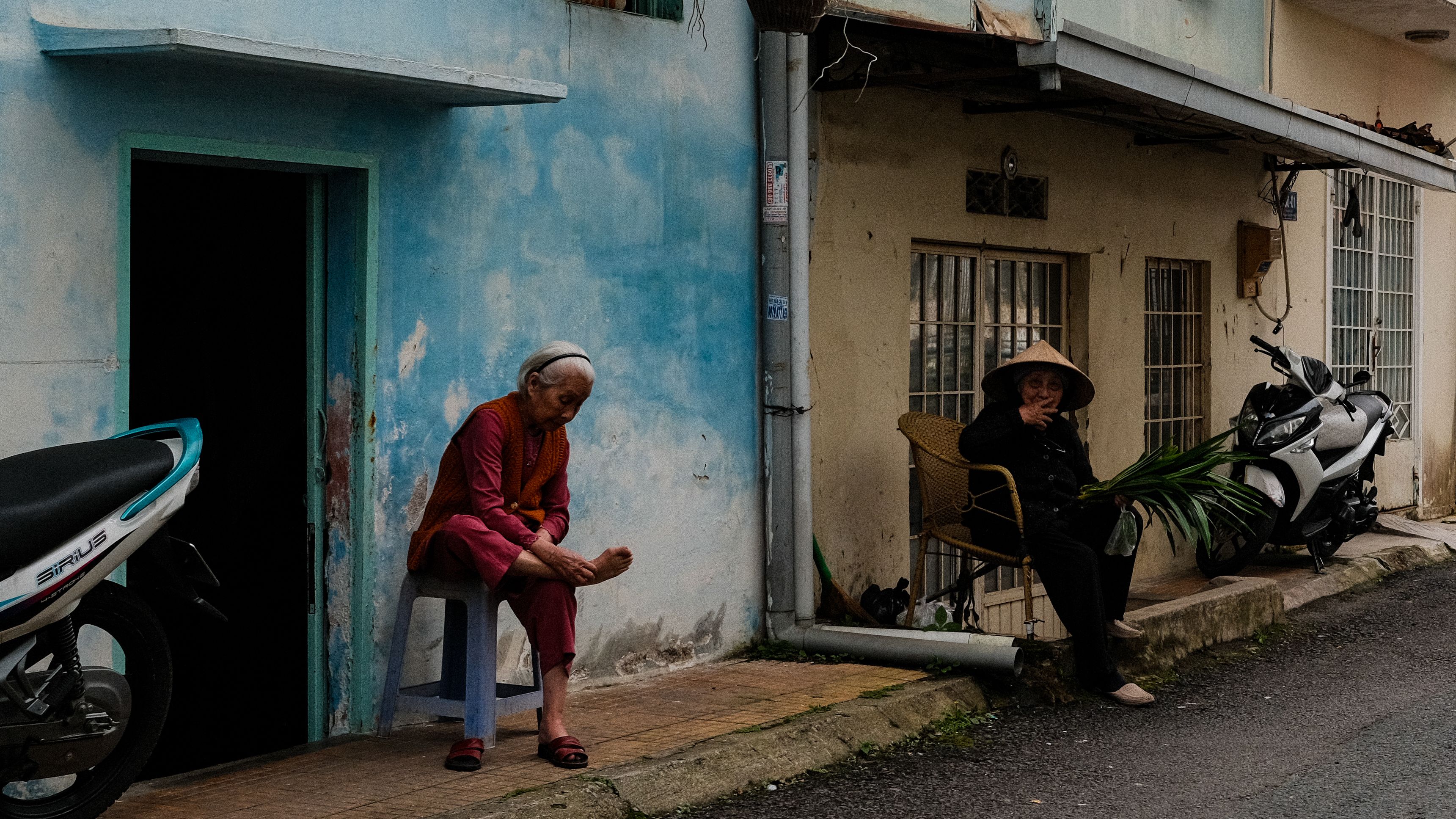 Elderly women sitting outside a house in Da Lat, Vietnam, showcasing daily village life.