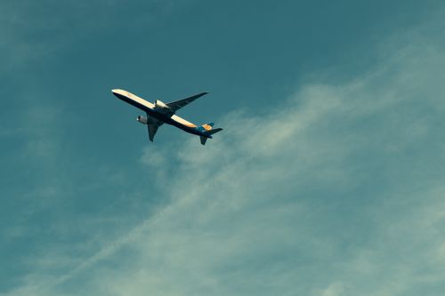 Free A lone airplane soaring through a blue sky, leaving a faint contrail behind. Stock Photo