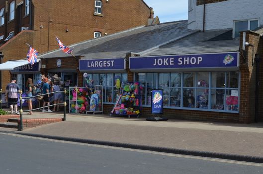 Outdoor view of people visiting the largest joke shop, adorned with colorful toys and Union Jack flags.