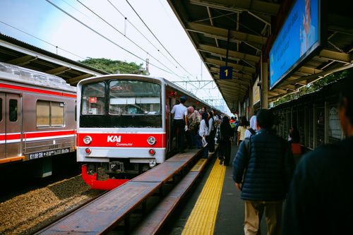 Free Passengers board KAI Commuter at a busy Jakarta train station platform during the day. Stock Photo