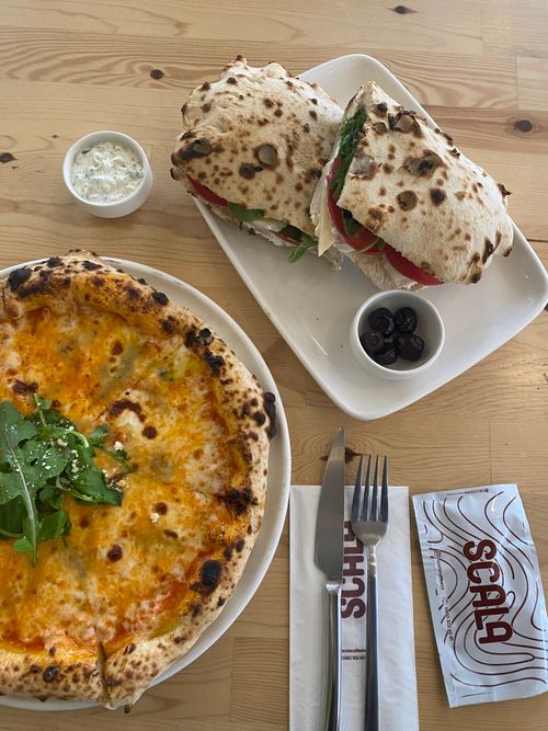 Free A mouth-watering Italian pizza with arugula and a fresh sandwich served in a cafe setting. Stock Photo