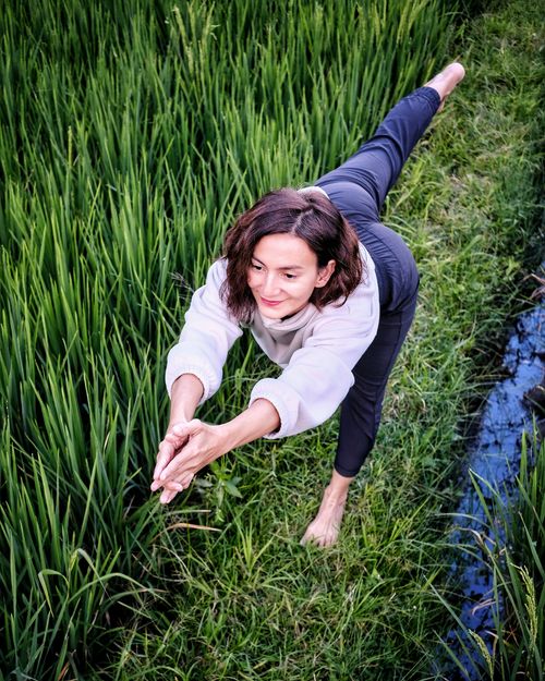 Free A woman in a yoga pose amidst a lush green field in Garut, Indonesia, blending fitness and nature. Stock Photo