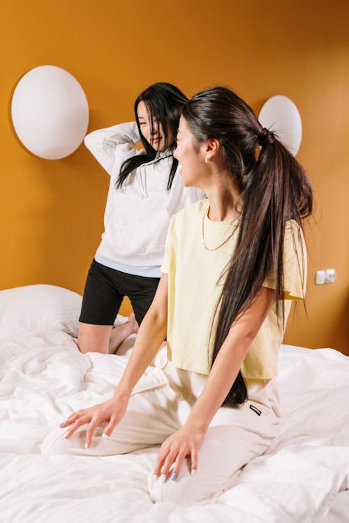Free Woman in White Shirt and Black Shorts Sitting on Bed Stock Photo