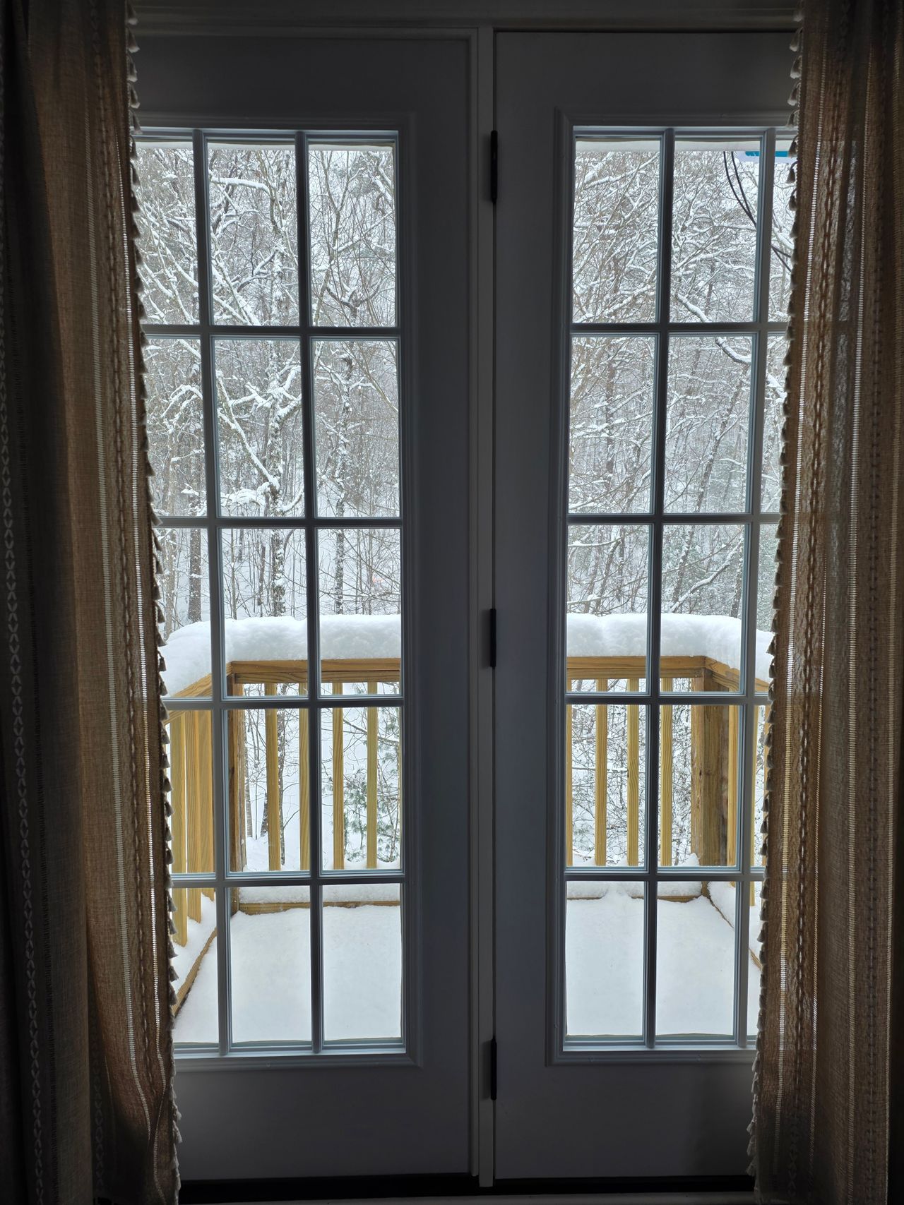 Glazed double doors with a view of a snowy deck and winter trees