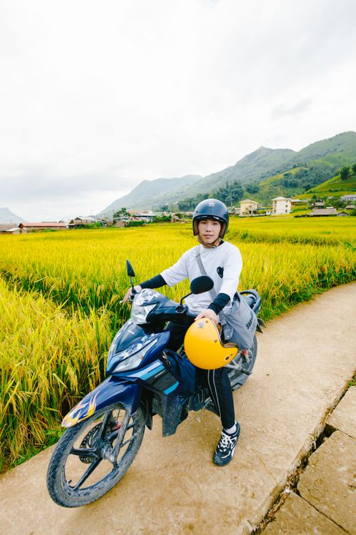 Free A young rider on a motorbike in a lush rice field during a bright day, showcasing rural travel. Stock Photo