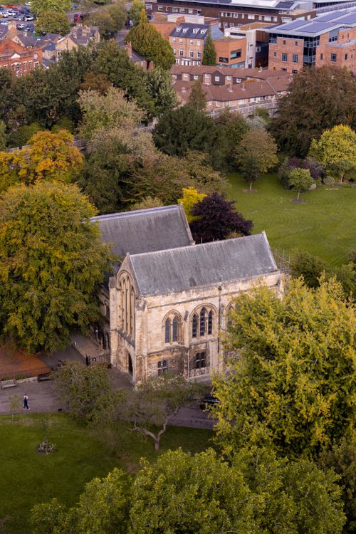 Free Aerial view of a historic stone church amidst autumn trees in a city park setting. Stock Photo