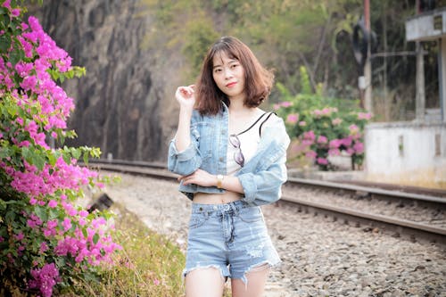 Woman In Blue Denim Shorts And White Long Sleeve Shirt Standing On Side Of Railroad