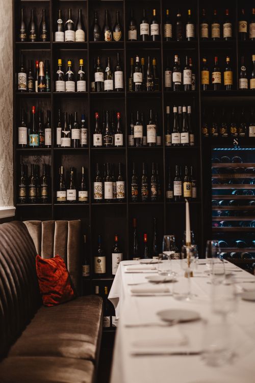Free Elegant dining setup in a cozy wine cellar featuring rows of wine bottles, perfect for a sophisticated evening. Stock Photo