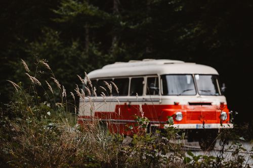 Free A vintage tour bus travels through the lush forest of Großschönau, Sachsen, Germany. Stock Photo