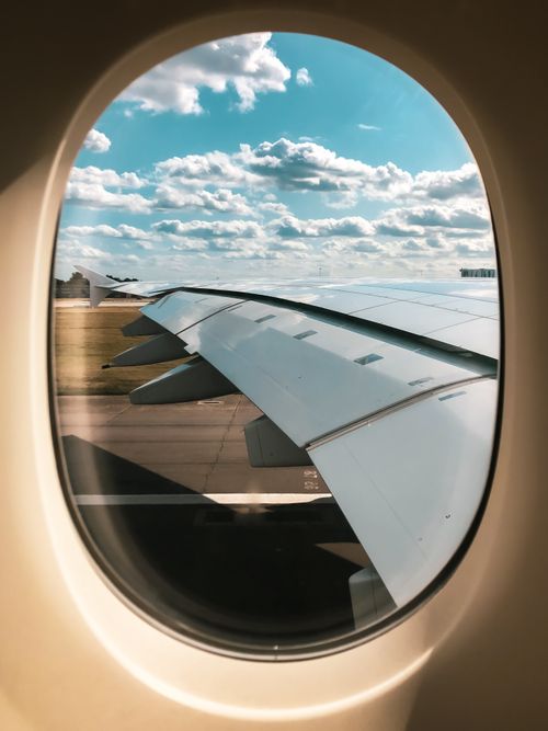 Free View of airplane wing and cloudy sky from passenger window, showcasing in-flight travel experience. Stock Photo