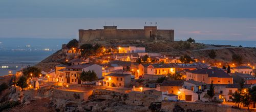 Free Chinchilla Castle at twilight, overlooking a lit medieval village in Albacete, Spain. Stock Photo