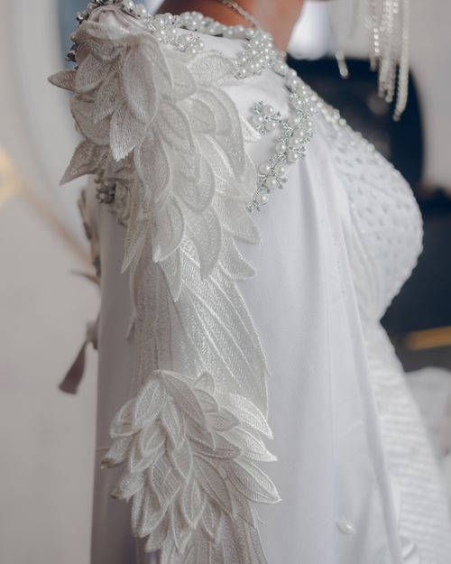 Free Close-up of an ornate white bridal dress with intricate floral embroidery, showcasing elegance and craftsmanship. Stock Photo
