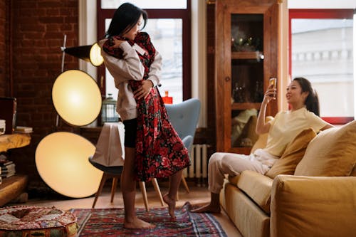 Free Woman in White Long Sleeve Shirt and Red Skirt Standing on Red and Brown Area Rug Stock Photo