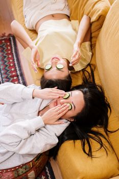 两位女士在家敷着舒缓的黄瓜面膜