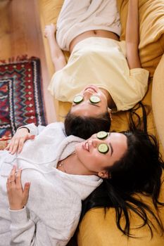 两个女人在家里沙发上放松地戴着黄瓜眼罩