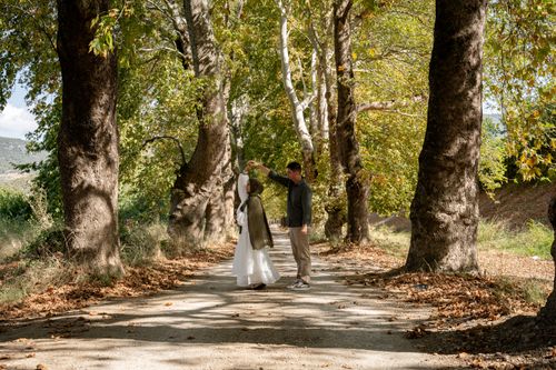 Free A couple enjoying a romantic moment dancing on a sunlit forest pathway surrounded by lush trees. Stock Photo